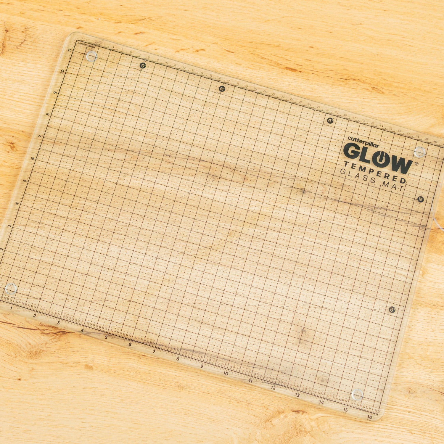 Grid-patterned cutting mat with 'Cutterpillar Glow' branding on a wooden surface