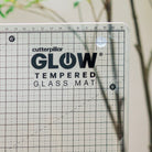 Cutterpillar Glow tempered glass mat with grid pattern on a neutral background