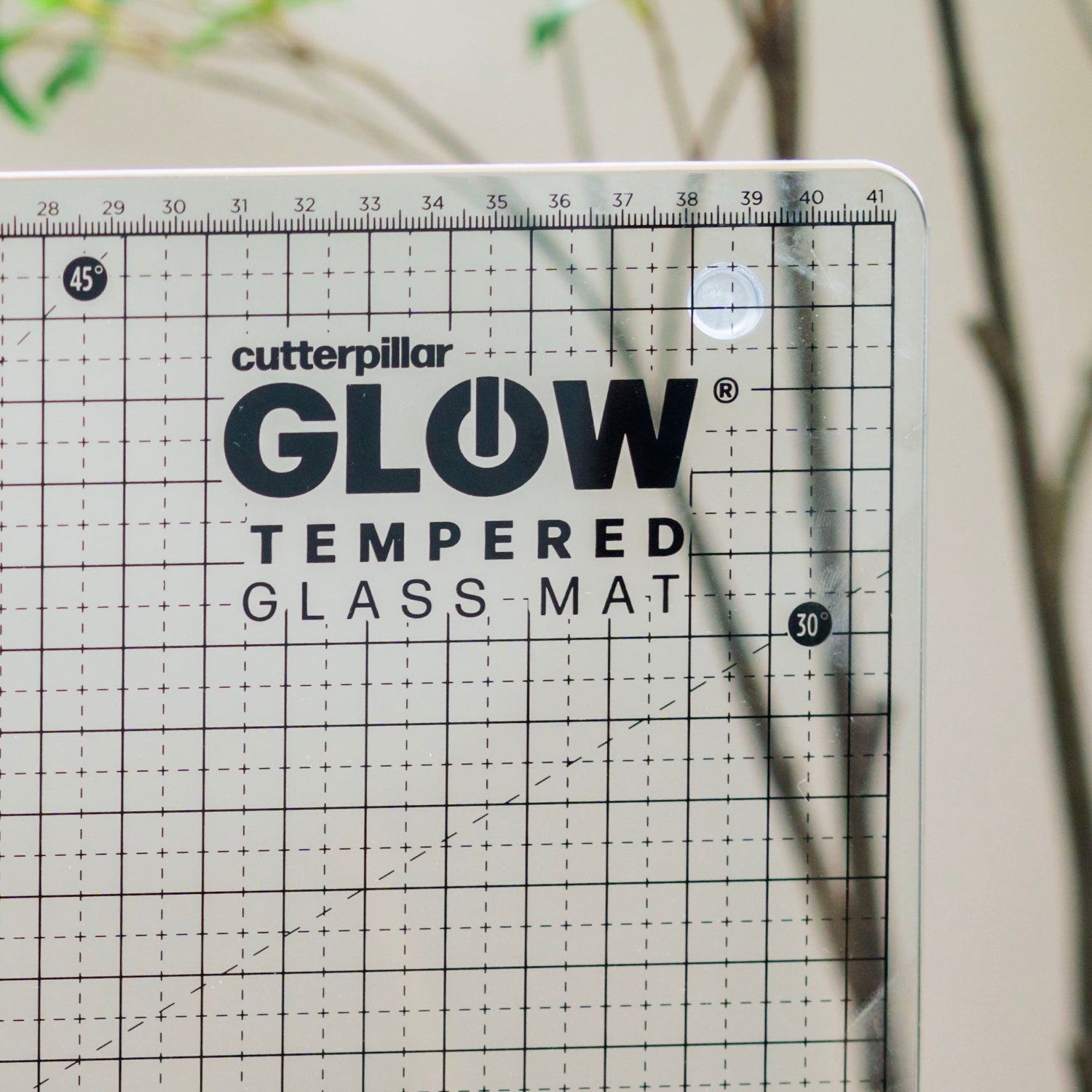 Cutterpillar Glow tempered glass mat with grid pattern on a neutral background