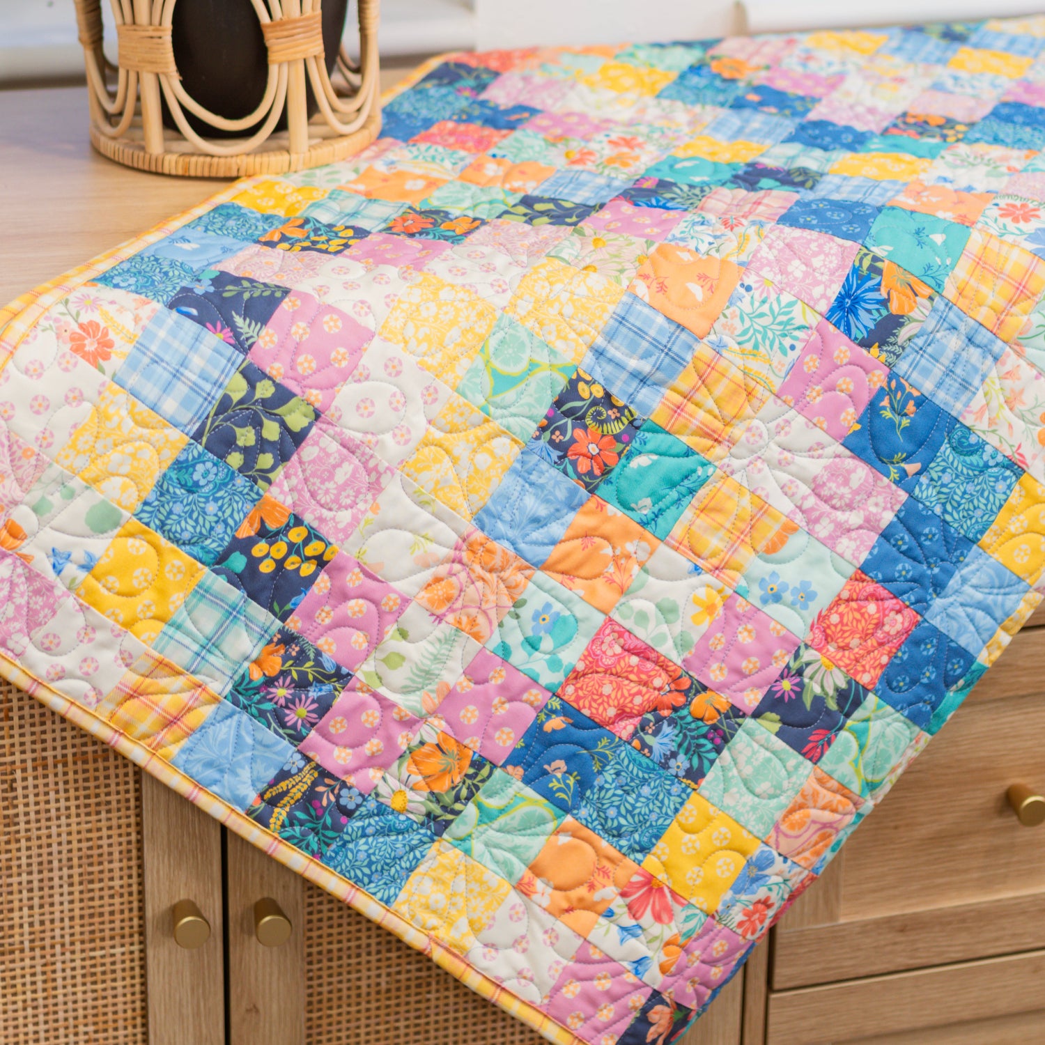 Colorful quilt on a wooden surface with a plant in the background
