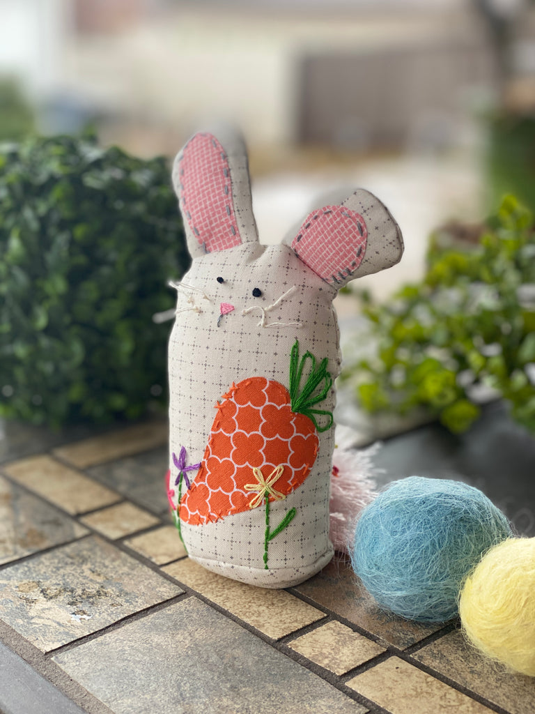 A bunny-shaped pincushion with hand-embroidered details.