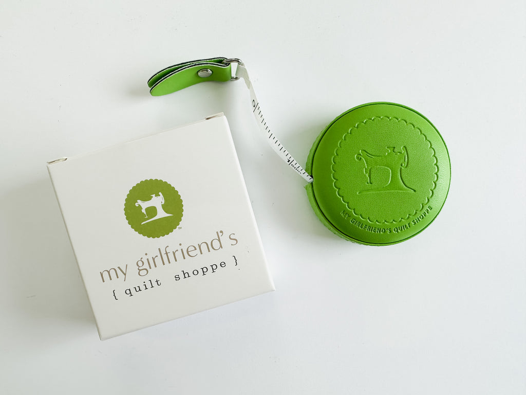 A round, green embossed leather tape measure.
