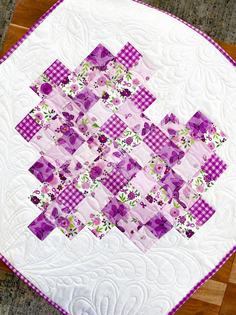 A quilted heart made up of purple squares. 